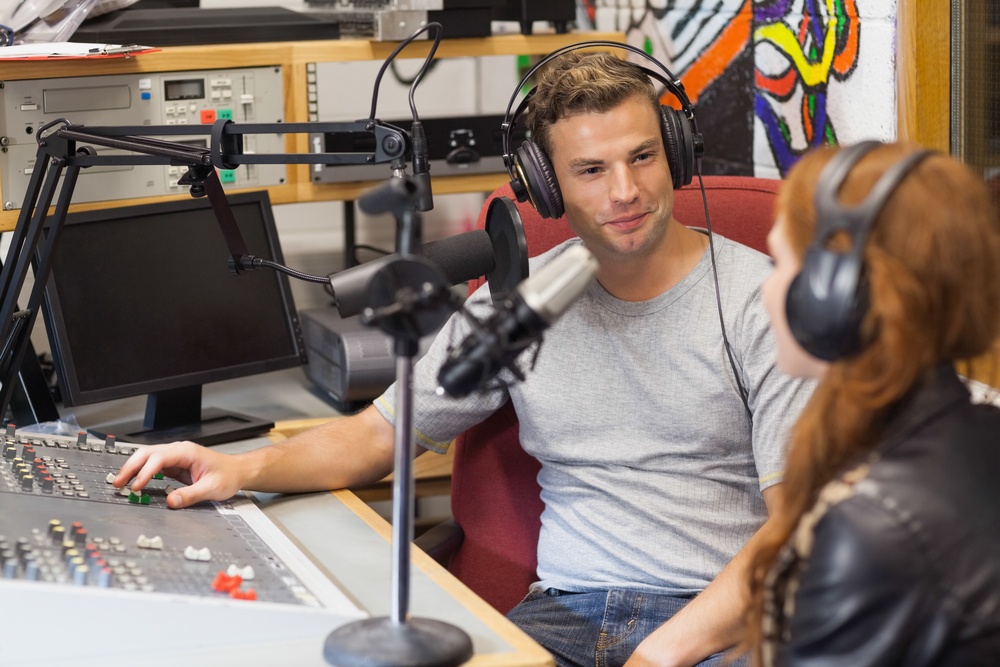 Attractive content radio host interviewing a guest in studio at college.jpeg