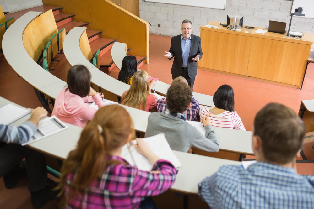 Elegant teacher with students sitting at the college lecture hall.jpeg